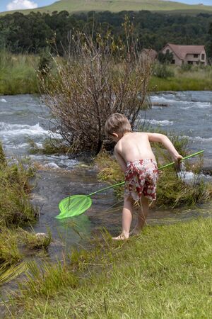 a close up view of a young child that playing in the water with a fishing pole の写真素材