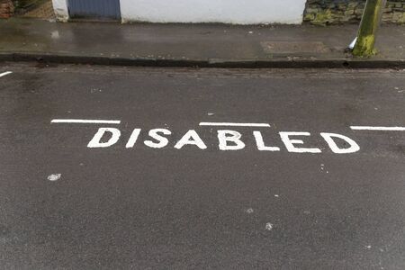 A close up view of a disabled parking area that has been marked off on the tar 