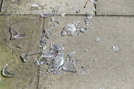 a close up view of a broken bottle that has been left on the sidewalkの写真素材