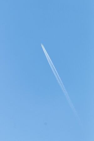 A view of the jet stream leading off the back of a passernger plane taking off の写真素材