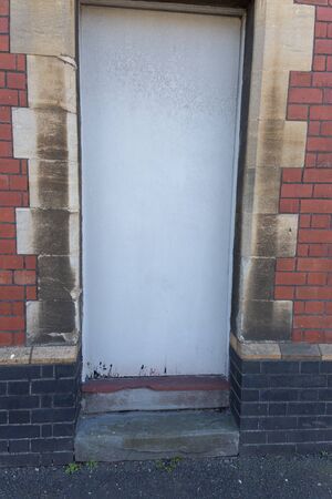 a close up view of a dirty white closed door with damaged at the bottom の写真素材
