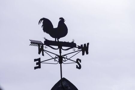 a close up view of a silhouette of a chicken with north, south, east and west directions weather meter の写真素材