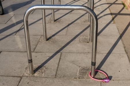 a close up view of a pink bike lock and chain connected to a metal bike postの写真素材