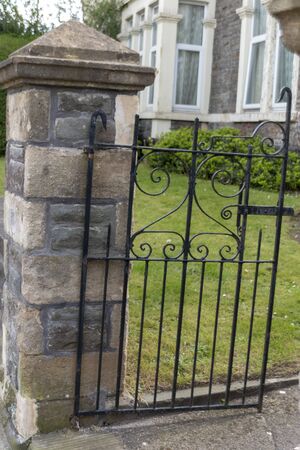 a close up view of a stone wall with a small black metal gate outside a flatの写真素材
