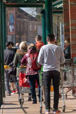 Bristol-March 2020-England- a close up view of people waitng in line to get into a supermarket due...