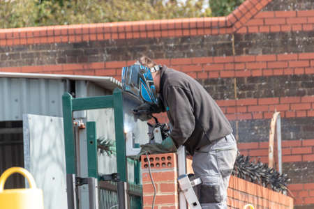 Bristol-April-2020-England, a close up view of a man welding a metal pipe to the main security gateのeditorial素材
