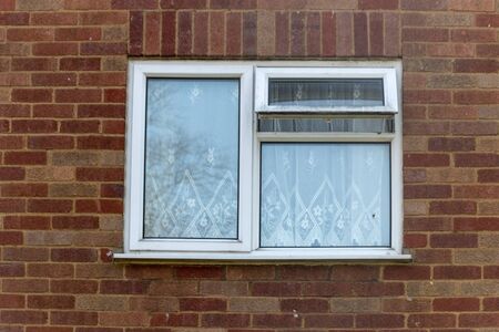 a close up view of a small side window on a brick face buliding with one portion open 