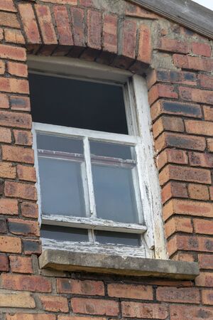 a close up view of a small side window on a brick face buliding with one portion open 