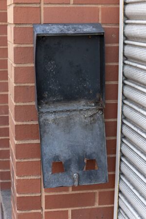 a close up view of a black metal box used for post or stoage outside a shop that has been burned and left openの写真素材