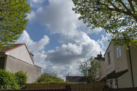 a close up view of the clouds in the blue sky though the middle of two buildings in a small villageの写真素材