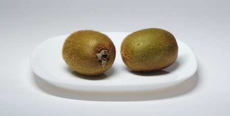 2 kiwi fruit on a white plate.の写真素材