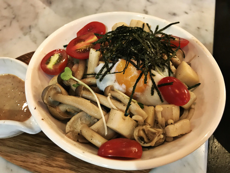 Stir fried variety mushroom topped with soft-boiled egg and dried seaweed.の写真素材