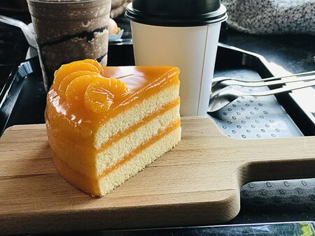 A piece of orange cake served on wooden butcher.の写真素材