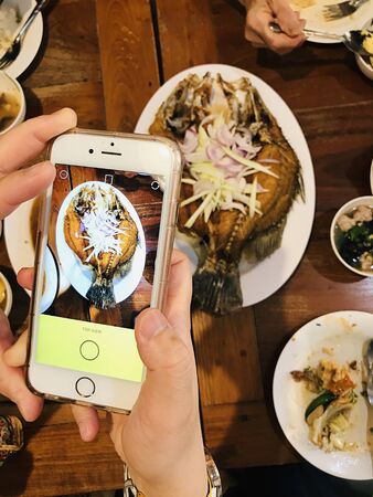 Take pictures of Thai style Deep Fried Sea Bass served with Green Mango Salad with mobile phone.