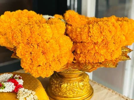 Marigold flower garlands on a gold color pedestal.