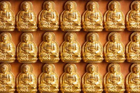 golden buddhas lined up along the wall of chinese templeの写真素材