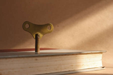 antique brass winder key standing on old book for the key of success conceptの写真素材