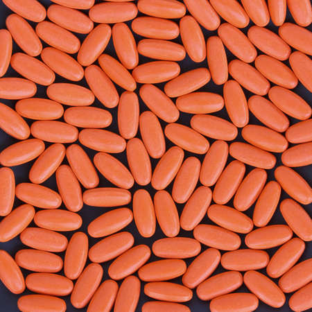 pile of orange color pills on black backgroundの写真素材