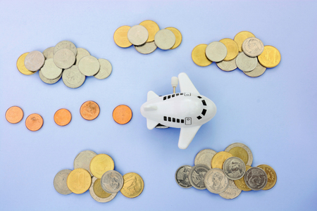 Coins stack with a plane toy isolated on blue background,concept for business and transportationの写真素材