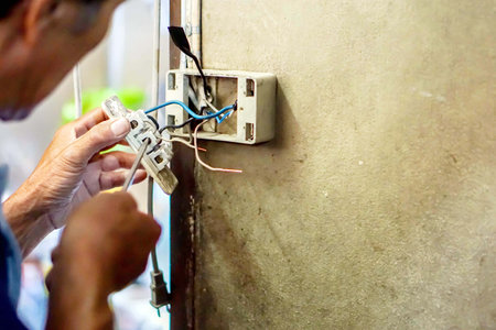 Closeup electric repair technician holding screwdriver and fixing the electric outlet on old...