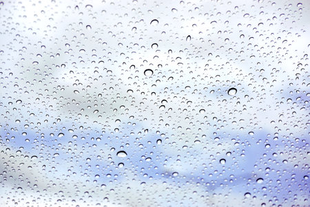 Raindrops on glass under the blue sky background.