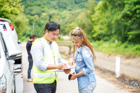 The insurance agent writing the details on the claim report form after the accident. Traffic accident insurance concept.の写真素材