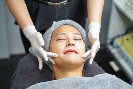 Closeup beauty woman making face spa and facial mask from cream to condition and treat the face in beauty clinic.の写真素材