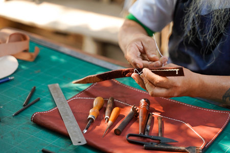 Closeup hand of leather craftsman is carefully to sew a leather belt for a customer., Leather...