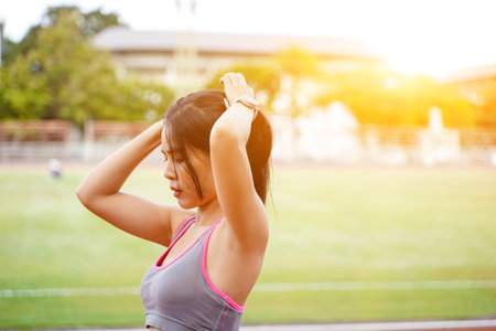 Young female get ready to exercise in the morning. at the football stadium with sunbeam and blurred background.の写真素材
