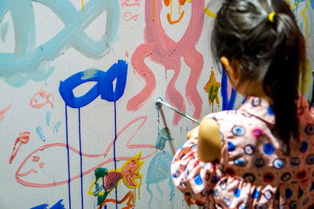 Lampang, Thailand, June 28 2019 : Closeup and back view of Asian girl drawing and decorating the walls of her new art classroomのeditorial素材