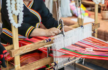 Closeup and crop hands of Thailander Hill tribe ladies are demonstration of weaving colorful fabric for tourists in her village.の写真素材