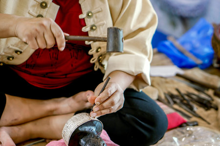 Closeup and crop Hands of Thailander demonstration of Carved silver water bowl at Chiang Mai,...