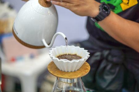Closeup hands of Barista making and pouring fresh dip coffee from the kettle for customer in a coffee shop.の写真素材