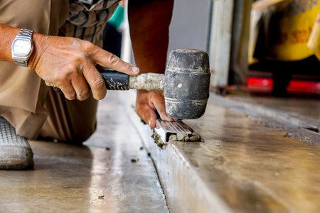Closeup hands of laborer holding Rubber hammer hit on aluminium lumber at construction site.