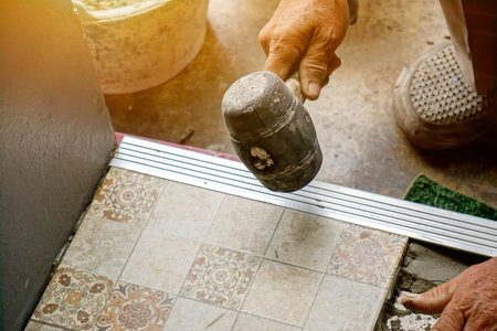 Closeup hands of laborer holding Rubber hammer hit on aluminium lumber and floor tiles at...
