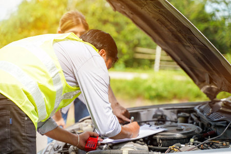 Closeup and crop auto repair checking engine and post a list of repairs according to customer orders with sun and lens flare background.の写真素材