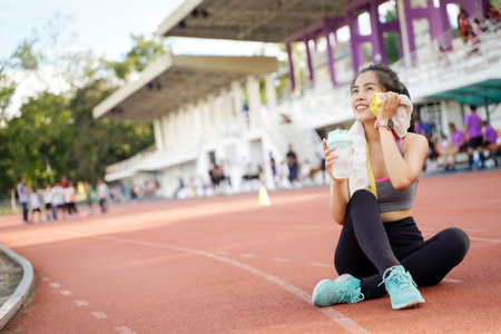 Young female relaxing after fitness training at the football stadium. She have a beautiful smile.の写真素材