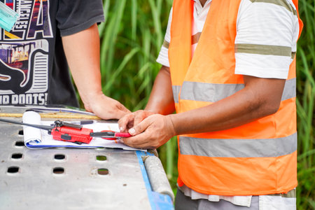 An engineer is using a cell phone to check prices and work meetings with workers at the construction...