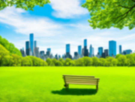 Blurred background of green nature public park, Blue sky and white cloud, Green grass field under sun lightの素材