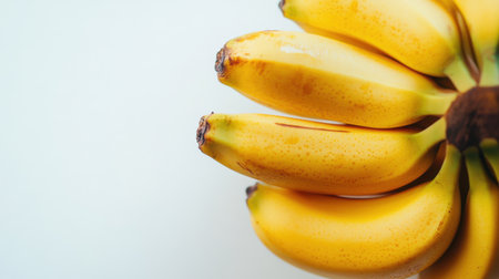 A close-up view of fresh ripe bananas on a clean white background, showcasing their vibrant yellow color and natural textures, perfect for healthy eating ideals.の素材