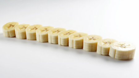 Neatly sliced bananas arranged on a white background highlight the freshness and simplicity of this delicious fruit, perfect for health-focused recipes or presentations.の素材
