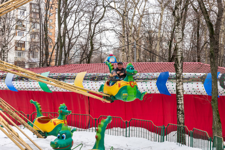 Winter 2015. Day. Russia. Moscow. Maslenitsa (pancake week). The Celebration of Maslenitsa (pancake week). The people in the park of amusements. Small children ridind on the carousel.のeditorial素材