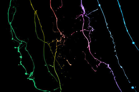 Colored paint splashes isolated on black backgroundの写真素材