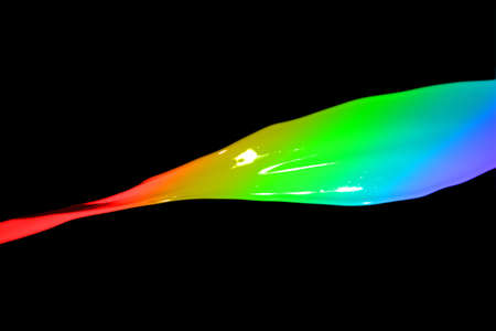 Colored paint splashes isolated on black backgroundの写真素材