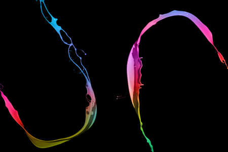 Colored paint splashes isolated on black backgroundの写真素材