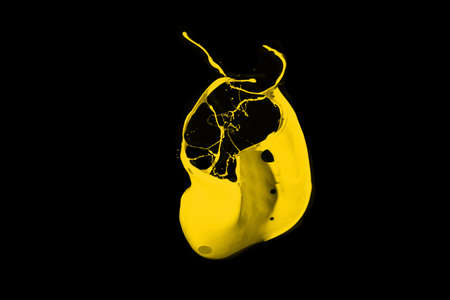 Yellow paint splash isolated on black background.
