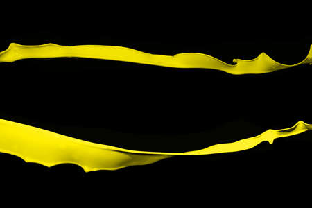 Yellow paint splash isolated on black background.の写真素材