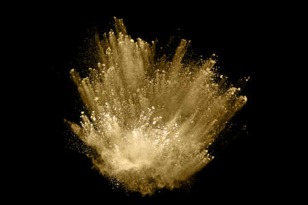 Golden powder explosion on black background. Freeze motion.
