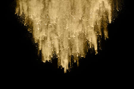 Golden powder explosion on black background. Freeze motion.