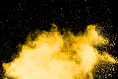 Freeze motion of yellow dust explosion isolated on black background.